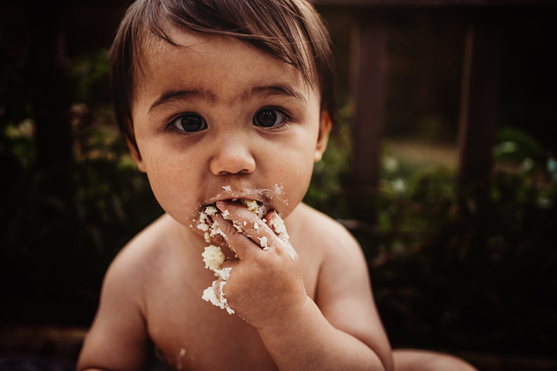 baby boy portrait eating cake outdoors