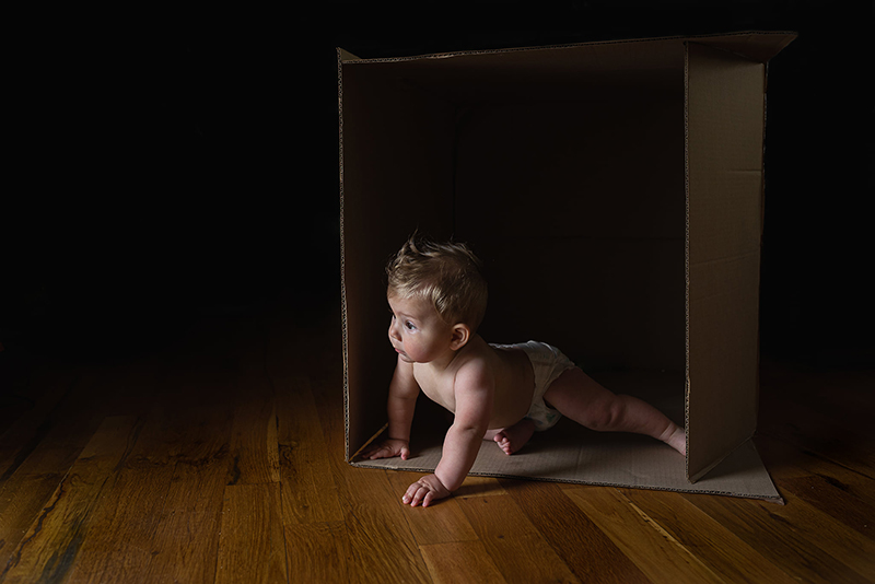 toddler boy playing in cardboard box