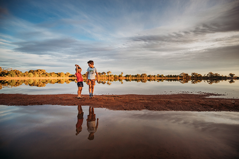 2 boys standing on river bed wearing shorts and tshirts