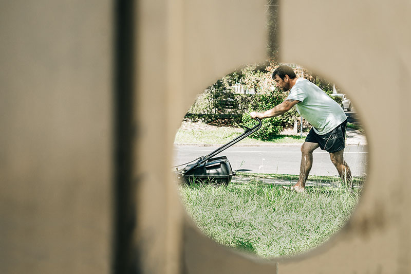 reflection of man mowing the lawn in circular mirror