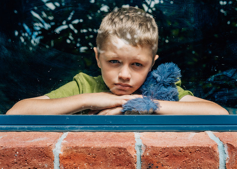 portrait of young boy looking out window