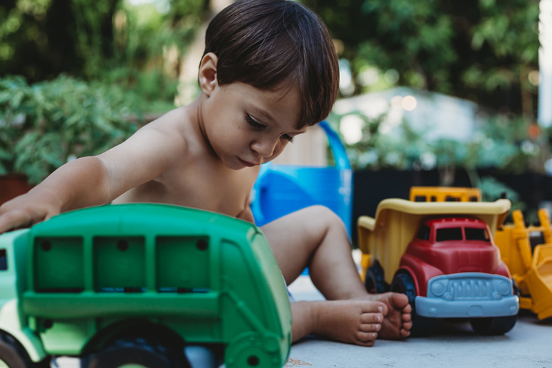 toddler boy sitting on ground with plastic trucks