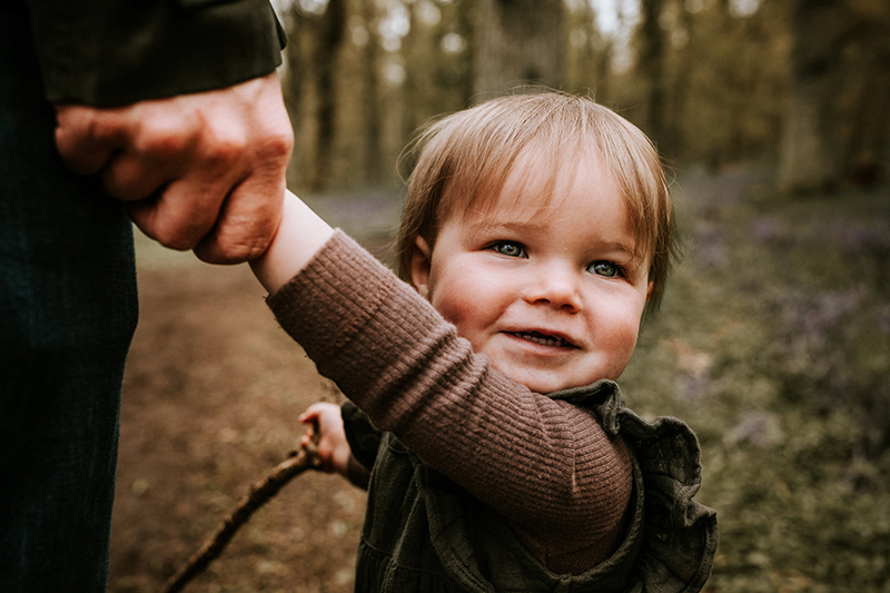 baby girl holding father's hand in a forest