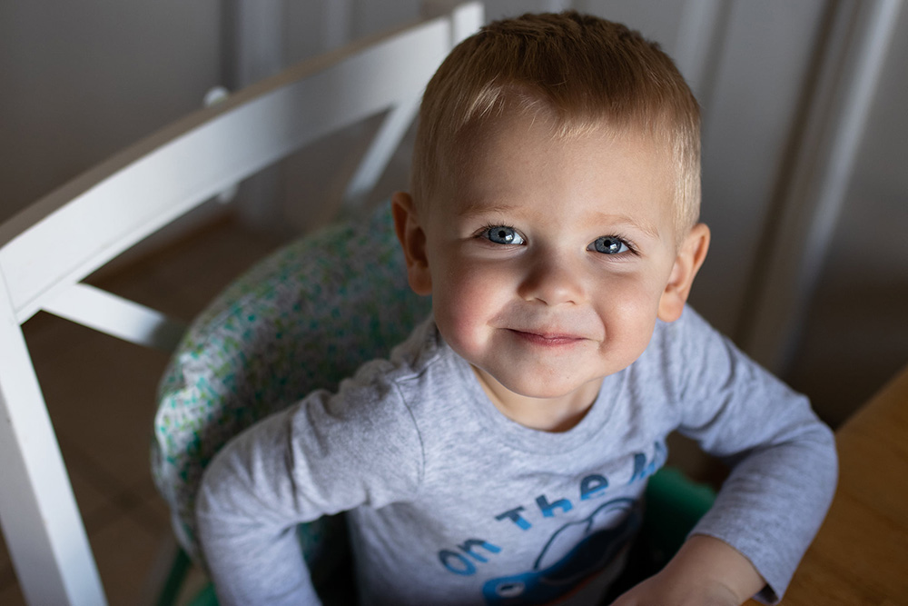 toddler boy in high chair smiling