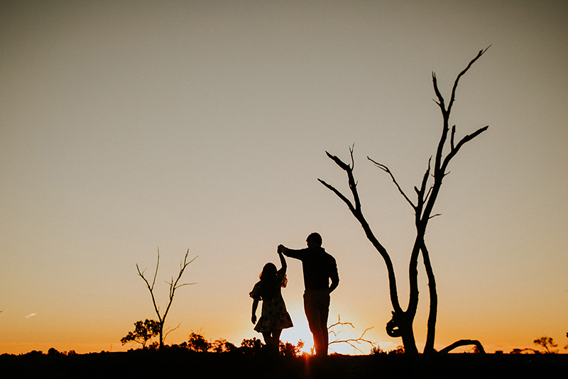 man twirling woman in silhouette with setting sun