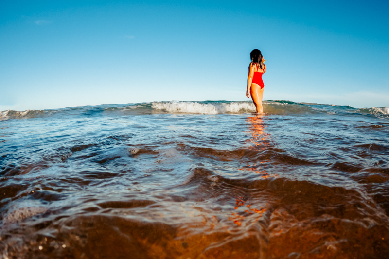 young girl in red swimsuit standing in the ocean