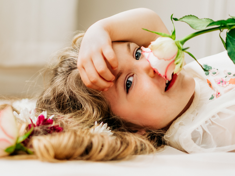 capture of young girl smelling a flower
