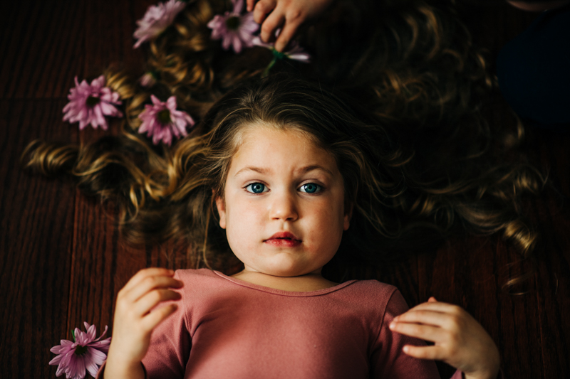 portrait of young girl lying down having flowers put in her hair