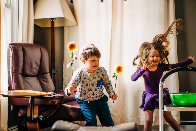 children having play fight with flowers indoors