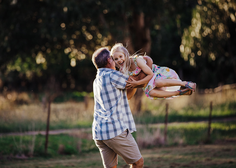 dad swinging young daughter around outdoors at golden hour