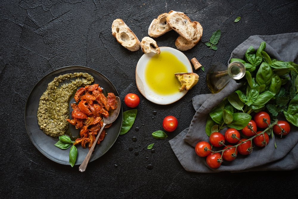 foot photo of rustic bread, tomatoes and basil on black background