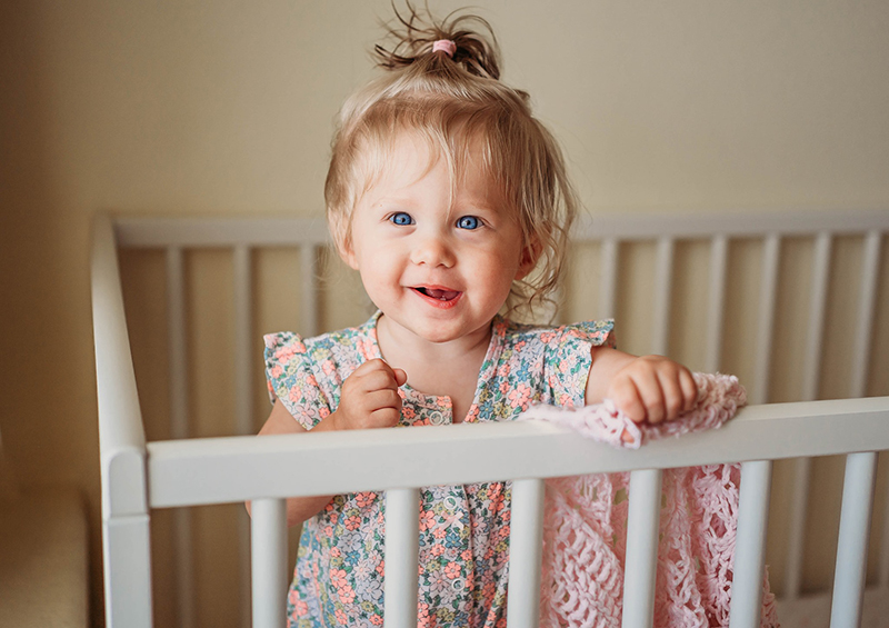 little girl smiles in her crib