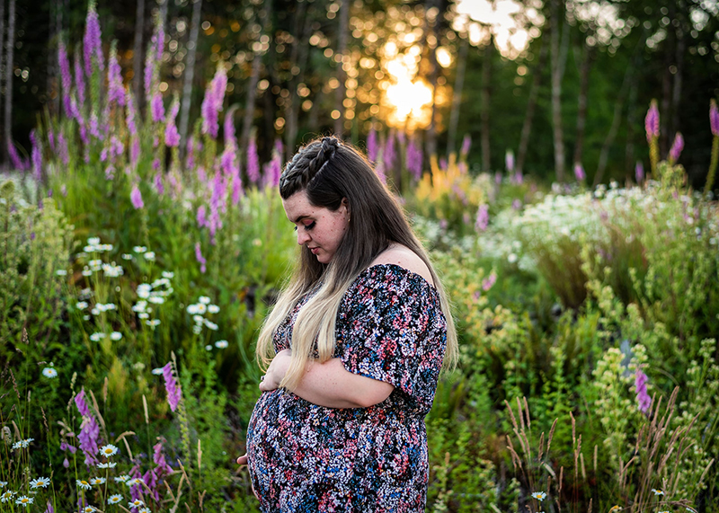 golden bokeh photo of pregnant lady in floral dress standing in field of flowers
