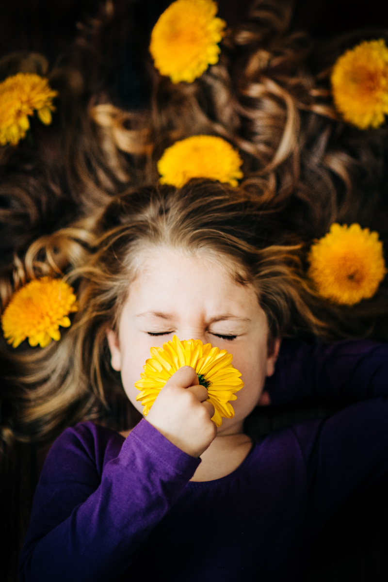portrait photography of young girl lying down smelling flower