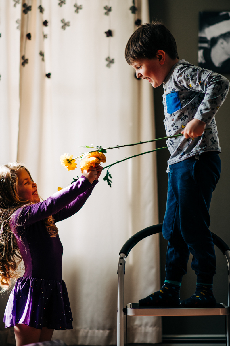 siblings having a play fight with flowers indoors 
