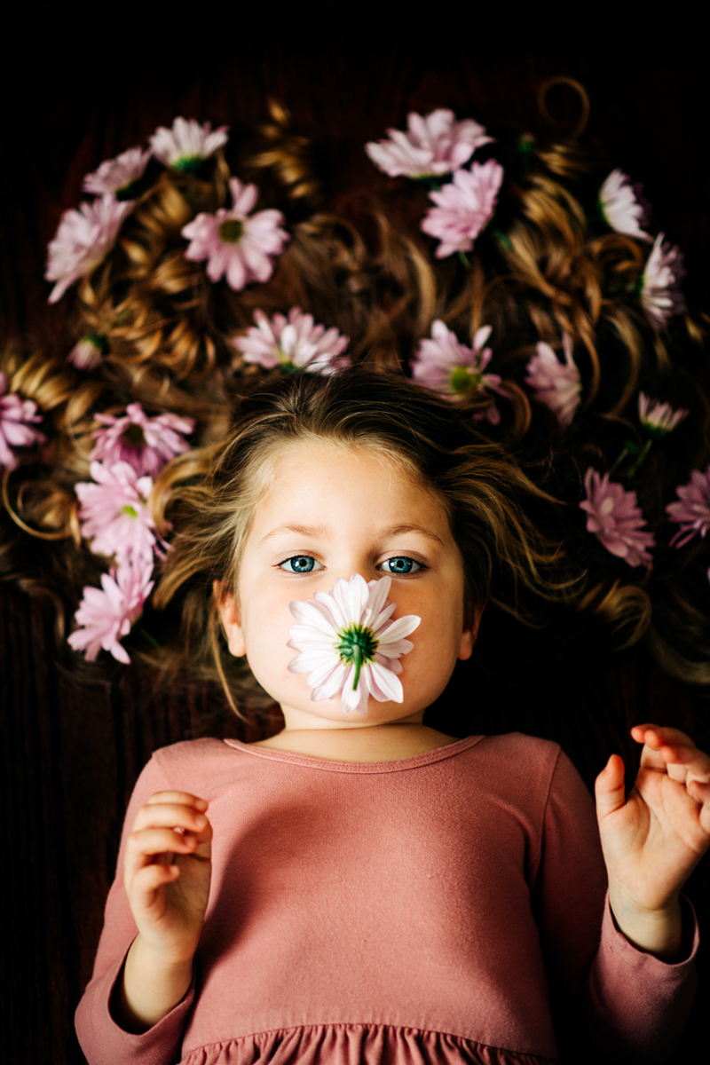 portrait ideas of young girl lying down smelling flower