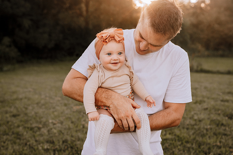 dad and baby girl wearing peach headband in a field