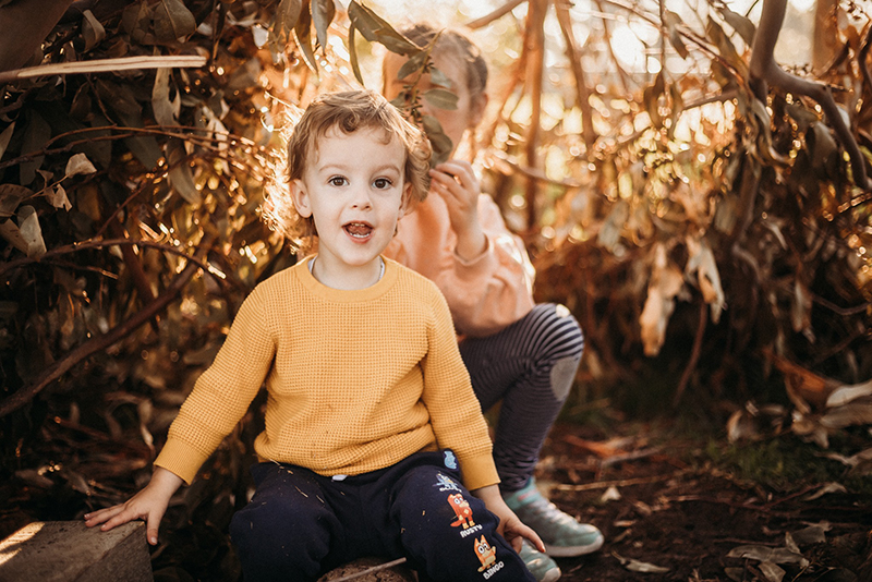golden hour bokeh photo of girl and toddler boy in yellow jumper