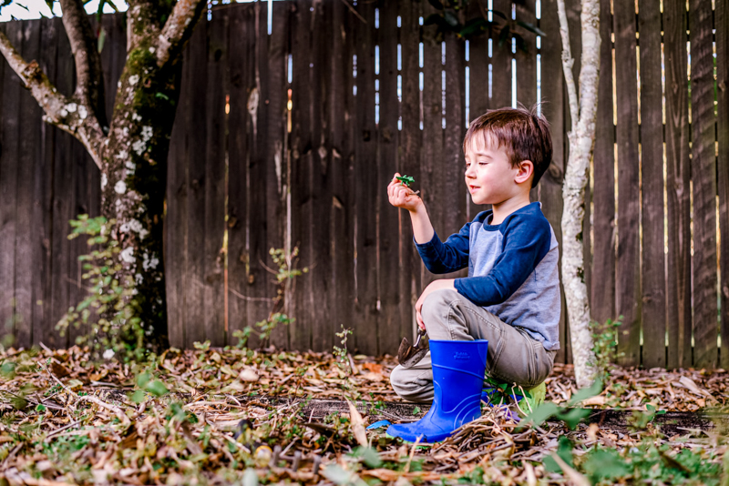 young boy in garden wearing blue gumboots