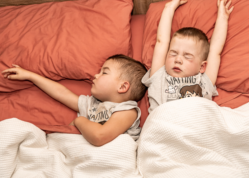 toddler twin boys asleep in big bed