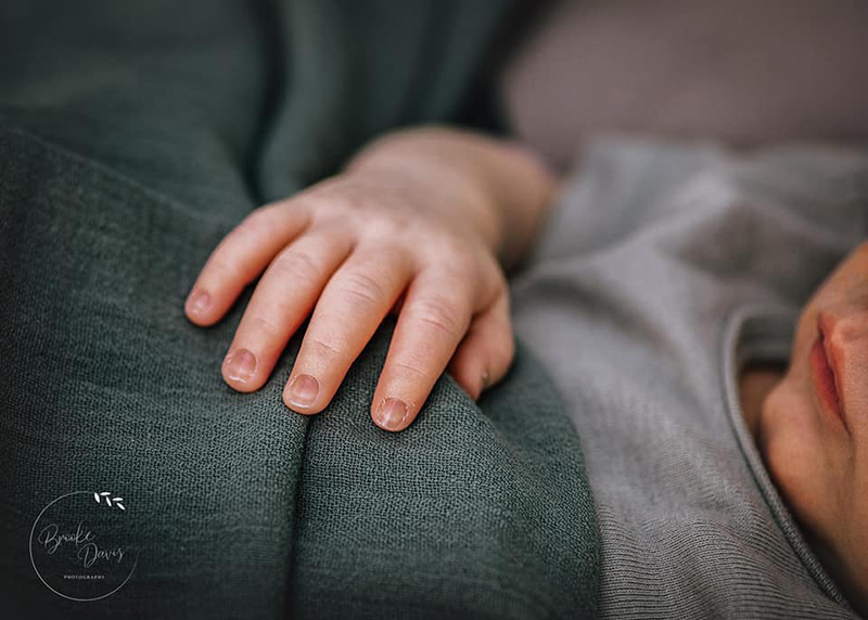 baby sleeping with green wrap and little fingers