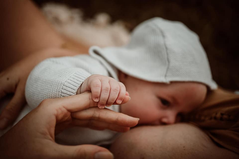baby breastfeeding and grabbing mum’s finger