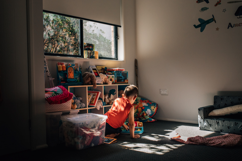 young boy playing with toys in pocket of light