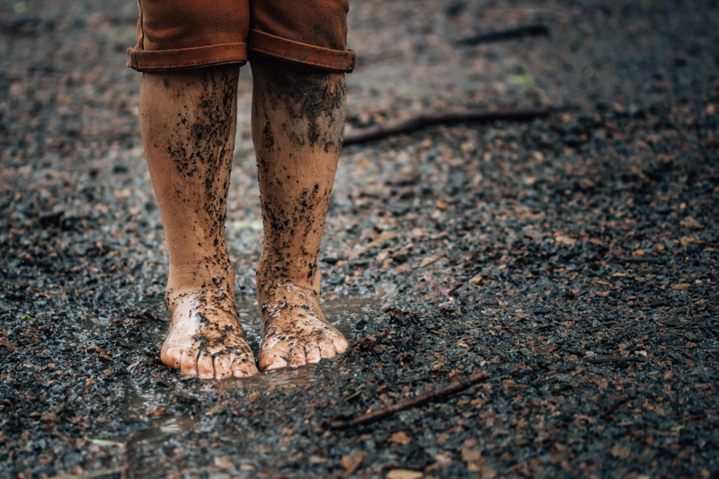 young boys feet and legs covered in mud