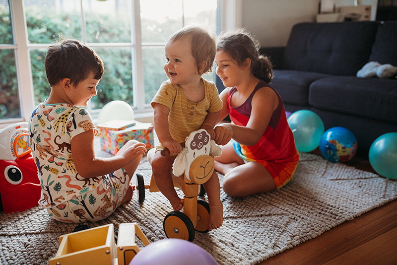 one baby and 2 children playing in a living room