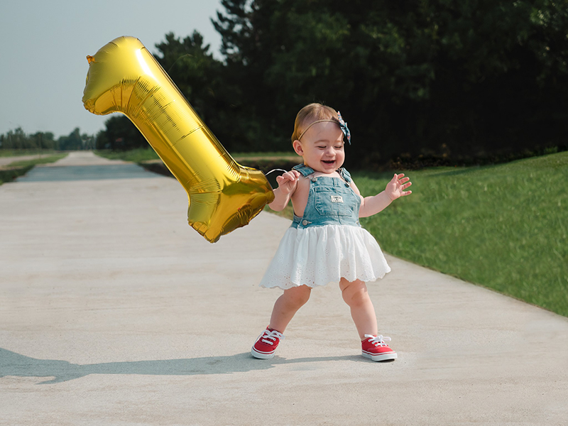 baby girl celebrating first year milestones holding a balloon