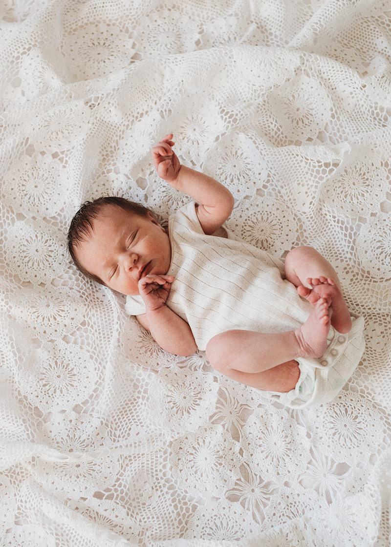 shot down photo of baby laying on white lace