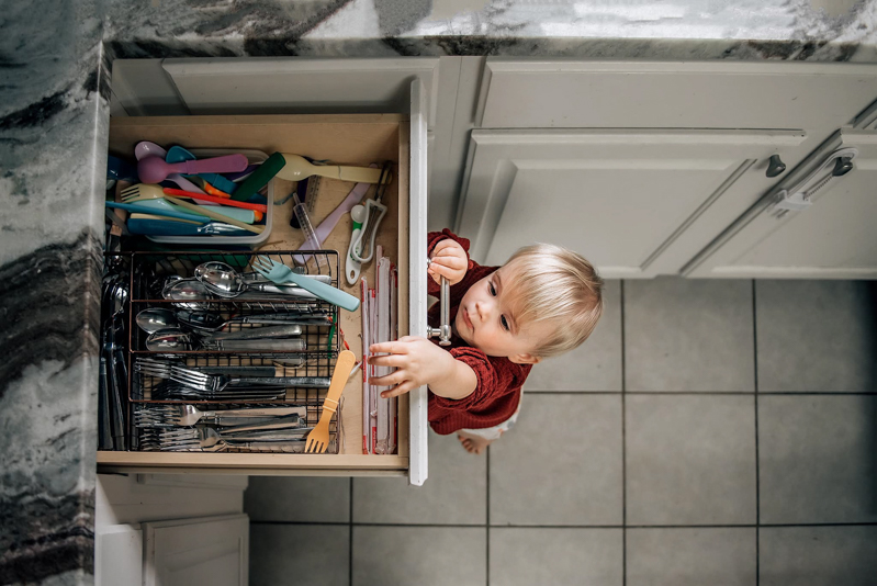 toddler girl reaching up into cutlery drawer