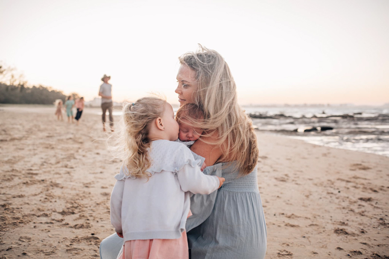portrait of mum with two young children on beach