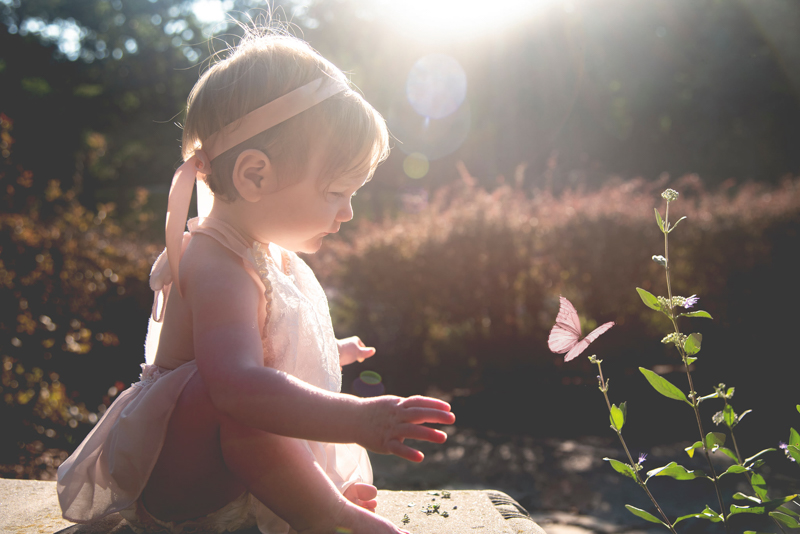 backlit portrait of toddler girl with butterfly