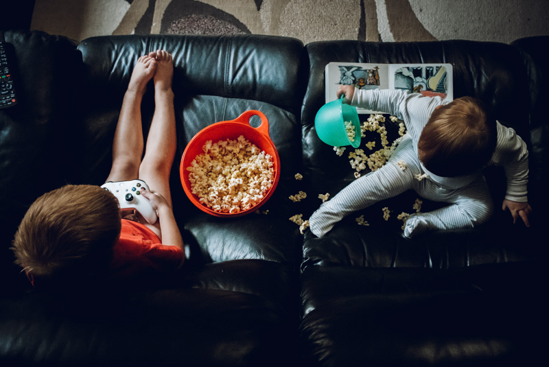 Top down picture of toddlers on couch with popcorn
