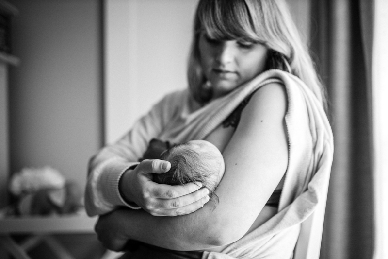 woman cradling newborn standing side on