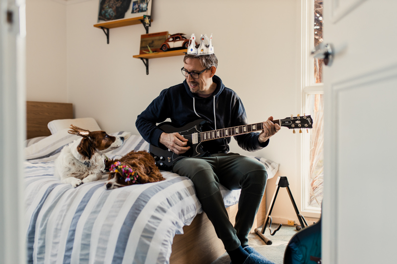 man with party hat playing guitar with dog