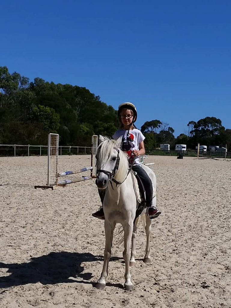 child riding white horse in full sun