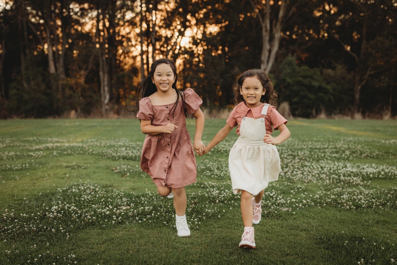  family photo of two young girls running at the park
