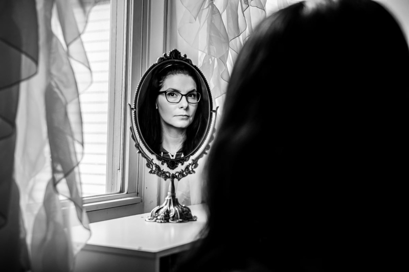 Black and white portrait of woman reflected in small decorative mirror