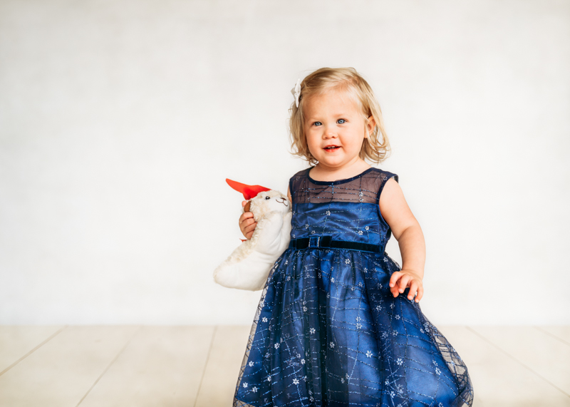 toddler girl in blue dress holding softie
