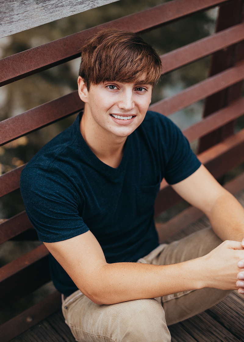 portrait of teen guy in blue shirt sitting on the ground