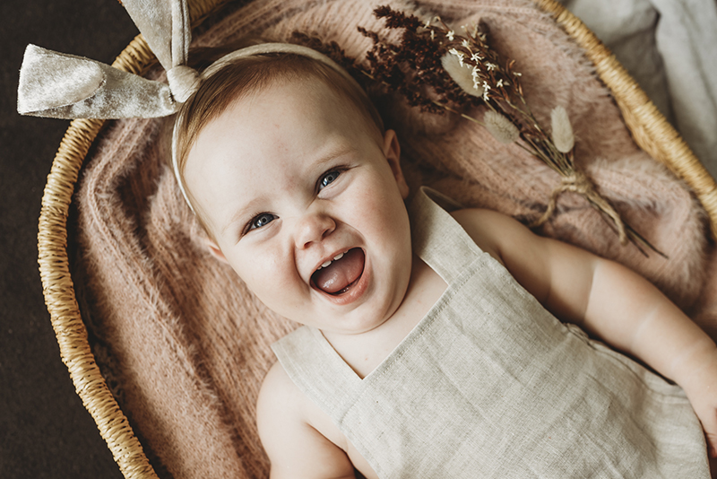 picture of baby on back in oatmeal romper