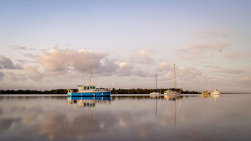 landscape photography image of boat on water with reflection of clouds