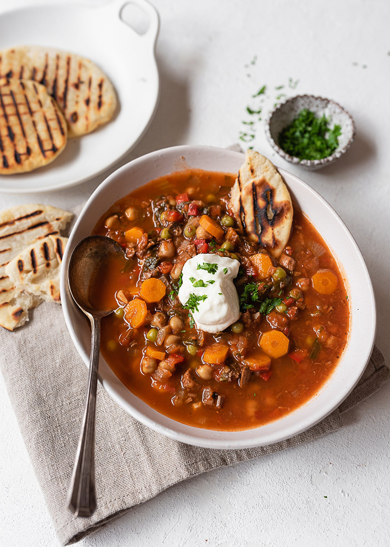 food photo of rustic stew with white platters and napkins