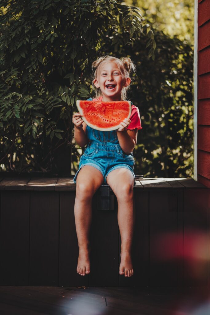 child laughing and smiling in photo with watermelon