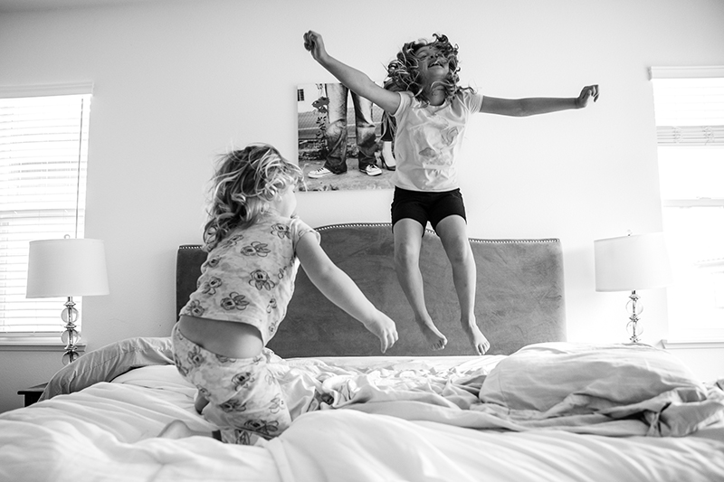 kids portrait two girls jumping on bed motion B&W