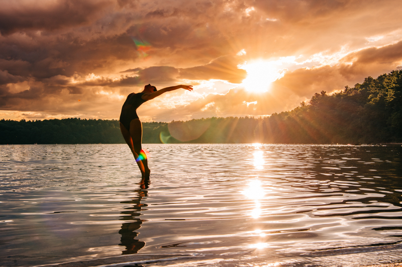 female dancer on surface of lake at sunset