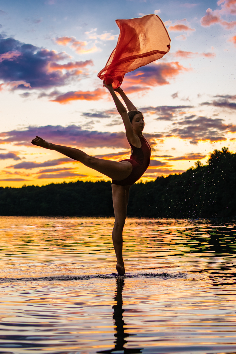 female dancer on surface of lake at sunset