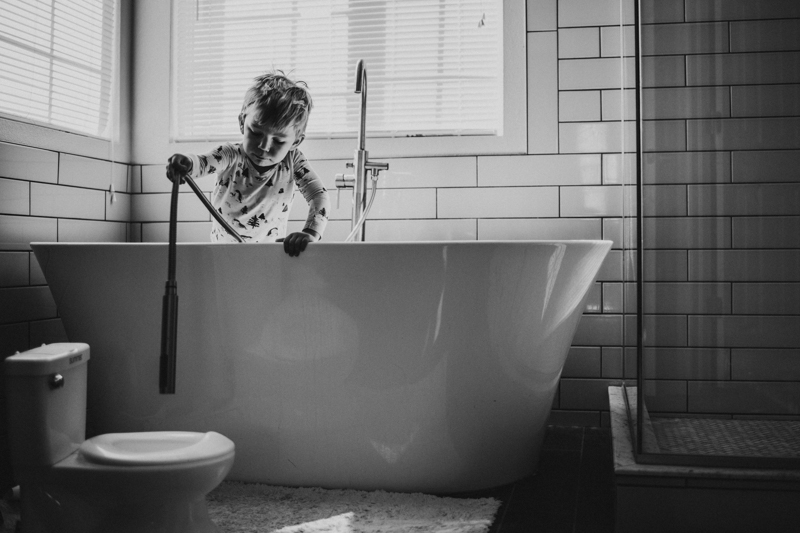 black and white portrait of toddler in pyjamas in bathtub